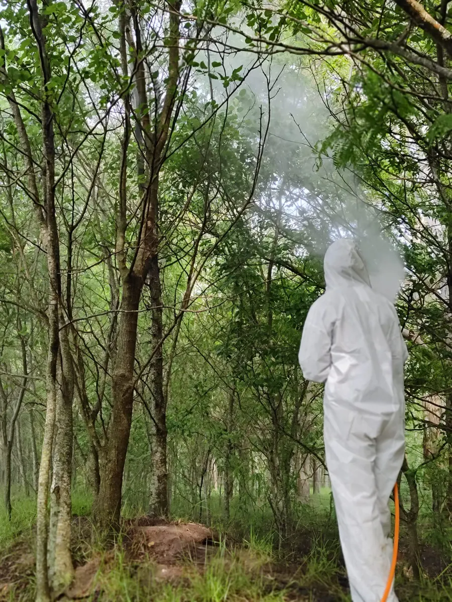 Operario con traje de protección dentro de un monte